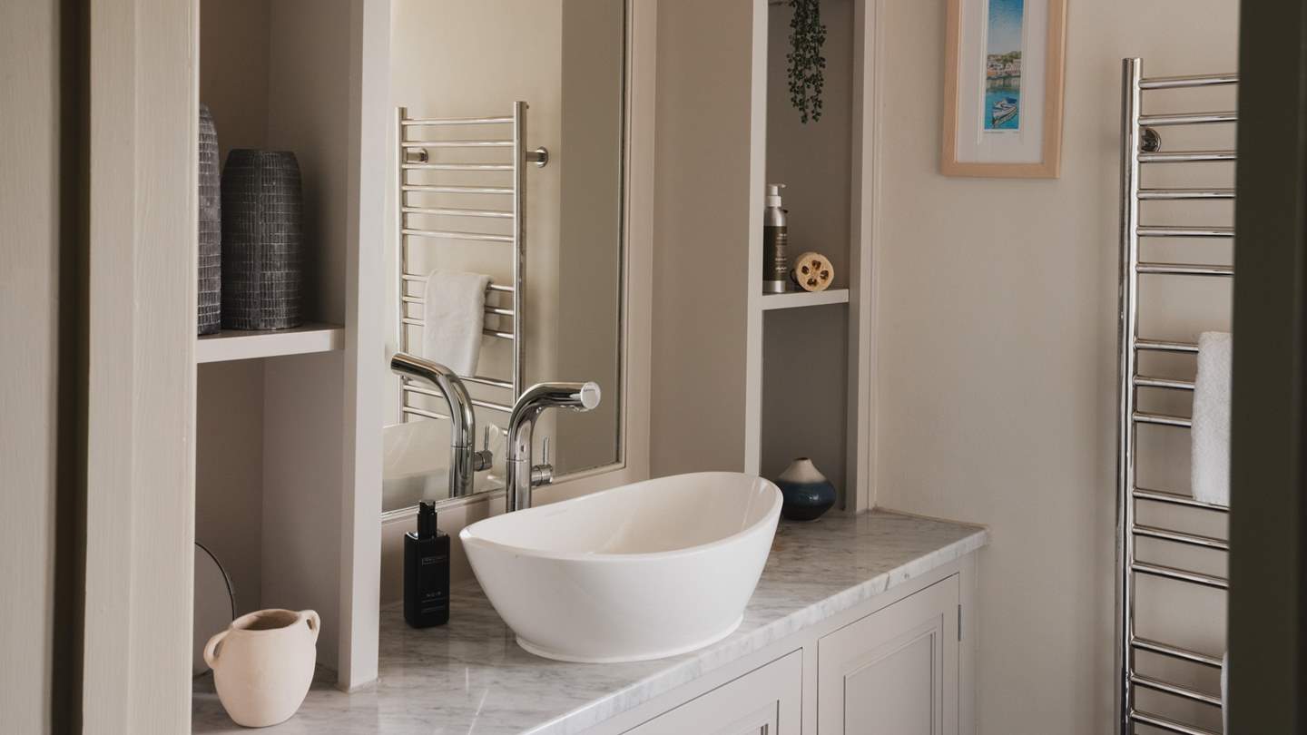 The family bathroom has a large walk-in shower, heated towel rail and soft-stone tiling