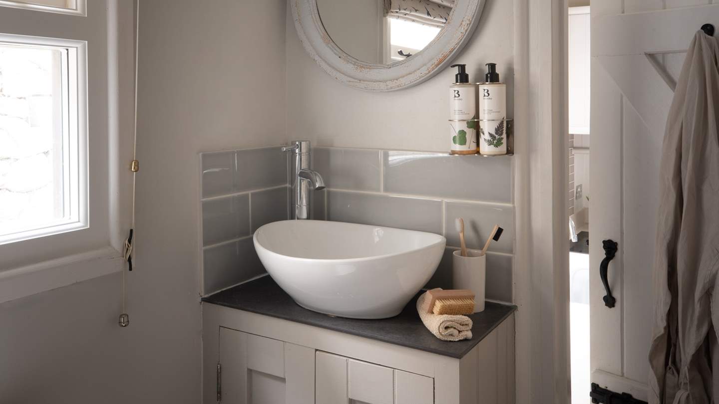 The pretty bathroom is on the ground floor with a three-quarter size bath and a shower over