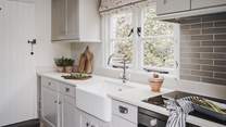 The beautiful kitchen with a white quartz worktop and decorated in soft shades of grey 