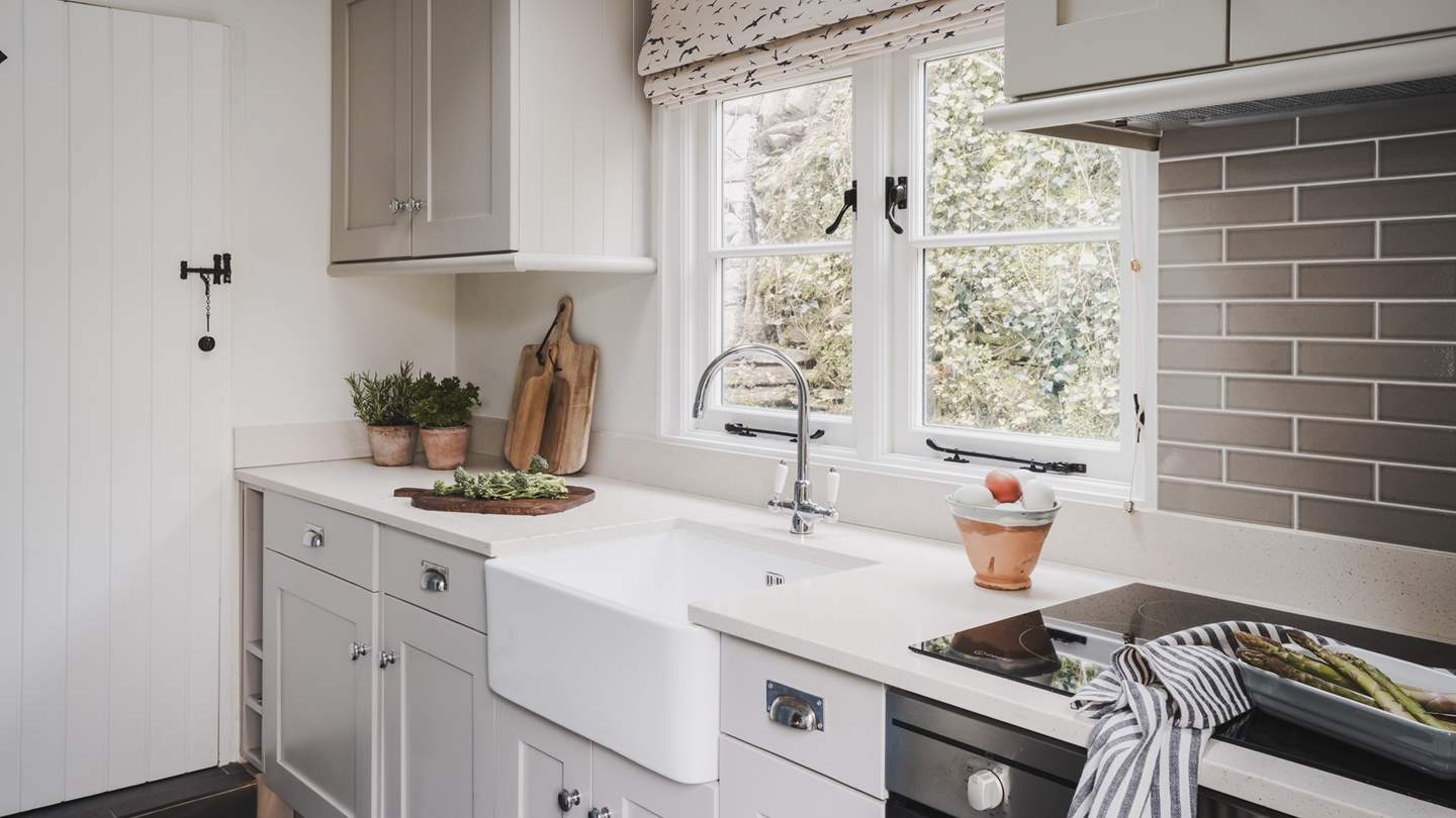 The beautiful kitchen with a white quartz worktop and decorated in soft shades of grey 