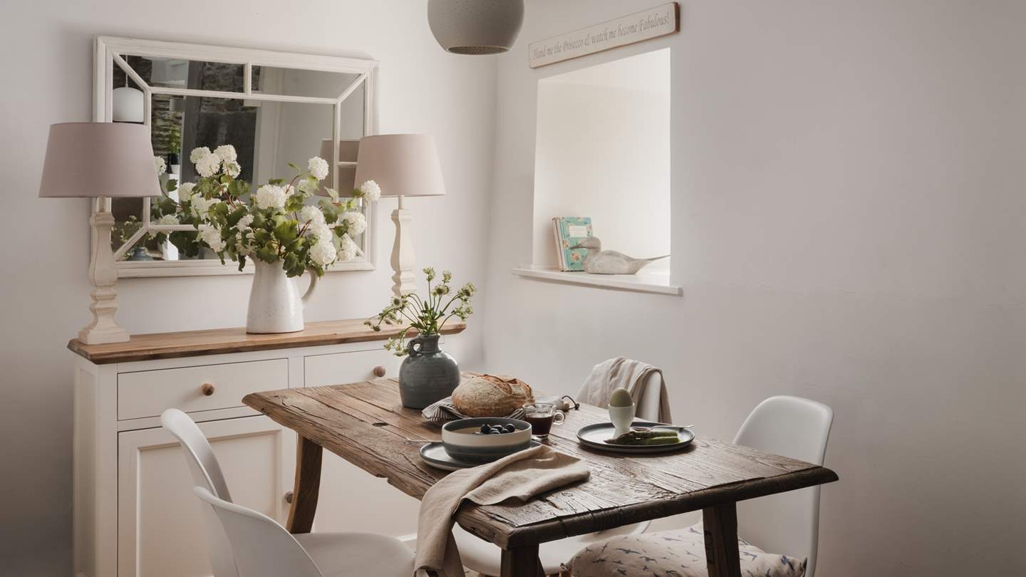 The dining space for four features a handsome wooden table with chic white chairs 