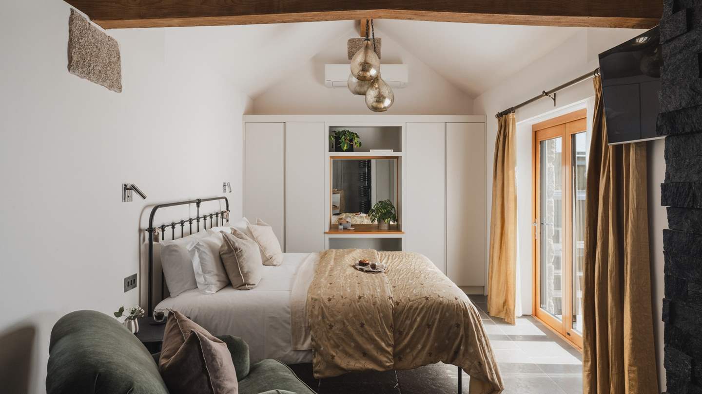 The bedroom features a palette of golden and olive hues, with plush textures like the comfortable chair