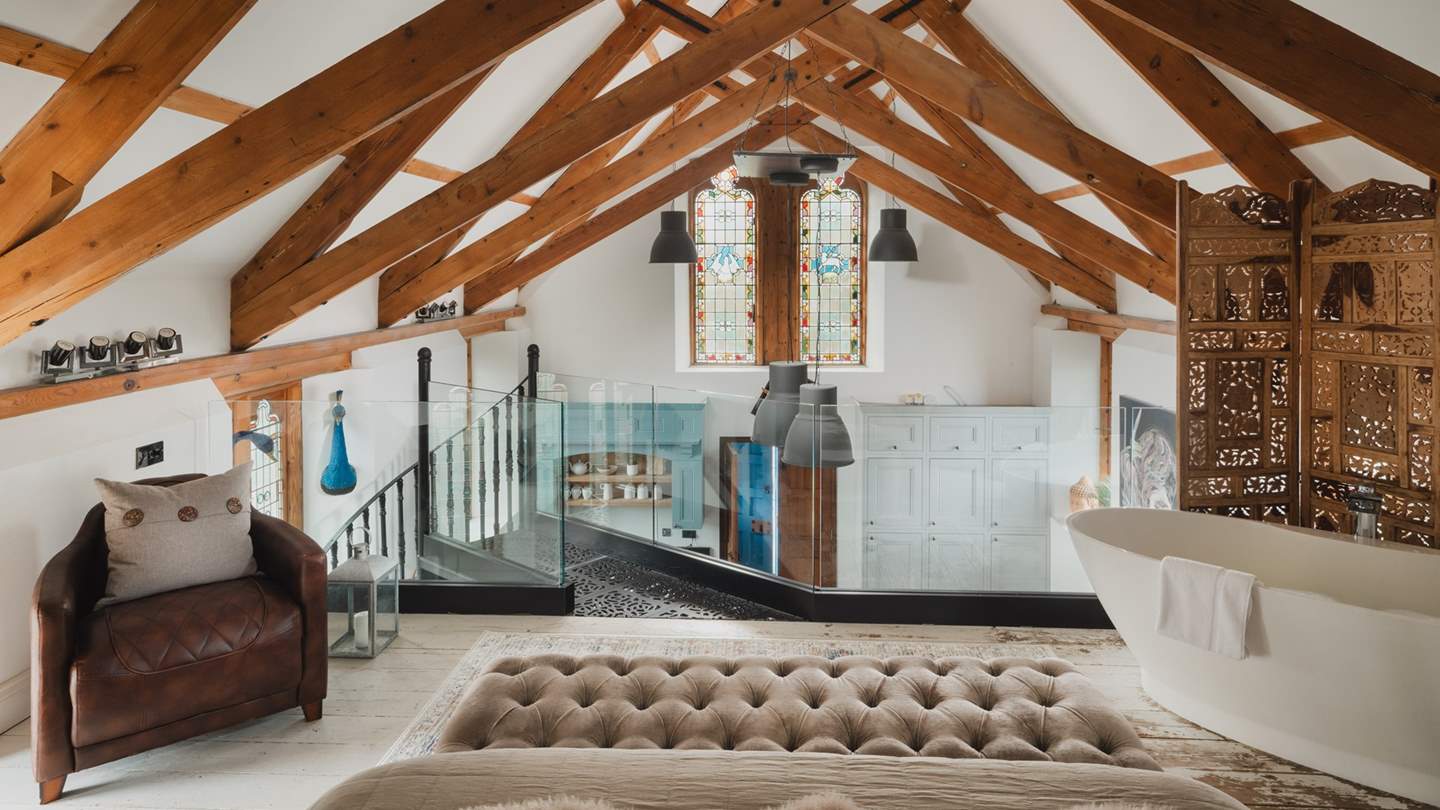 A wrought iron spiral staircase leads up to the mezzanine level where you’ll discover the gorgeous master bedroom with en suite