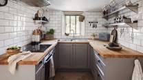 The dreamy kitchen features soft grey units, paired with an attractive wooden worktop