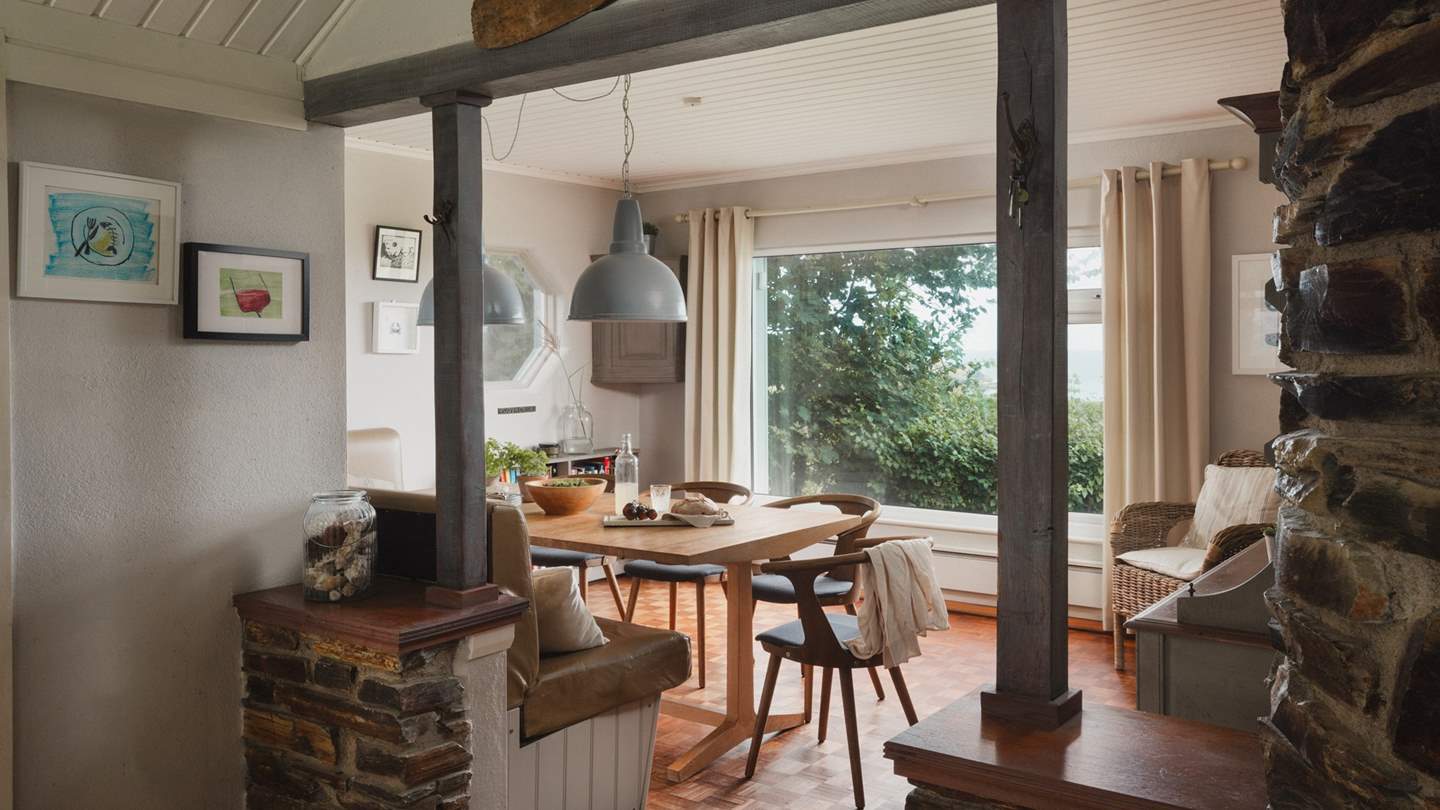 The adjoining dining room features a grand Welsh dresser, with a trestle-style dining table and leather bonquette seating for meals together