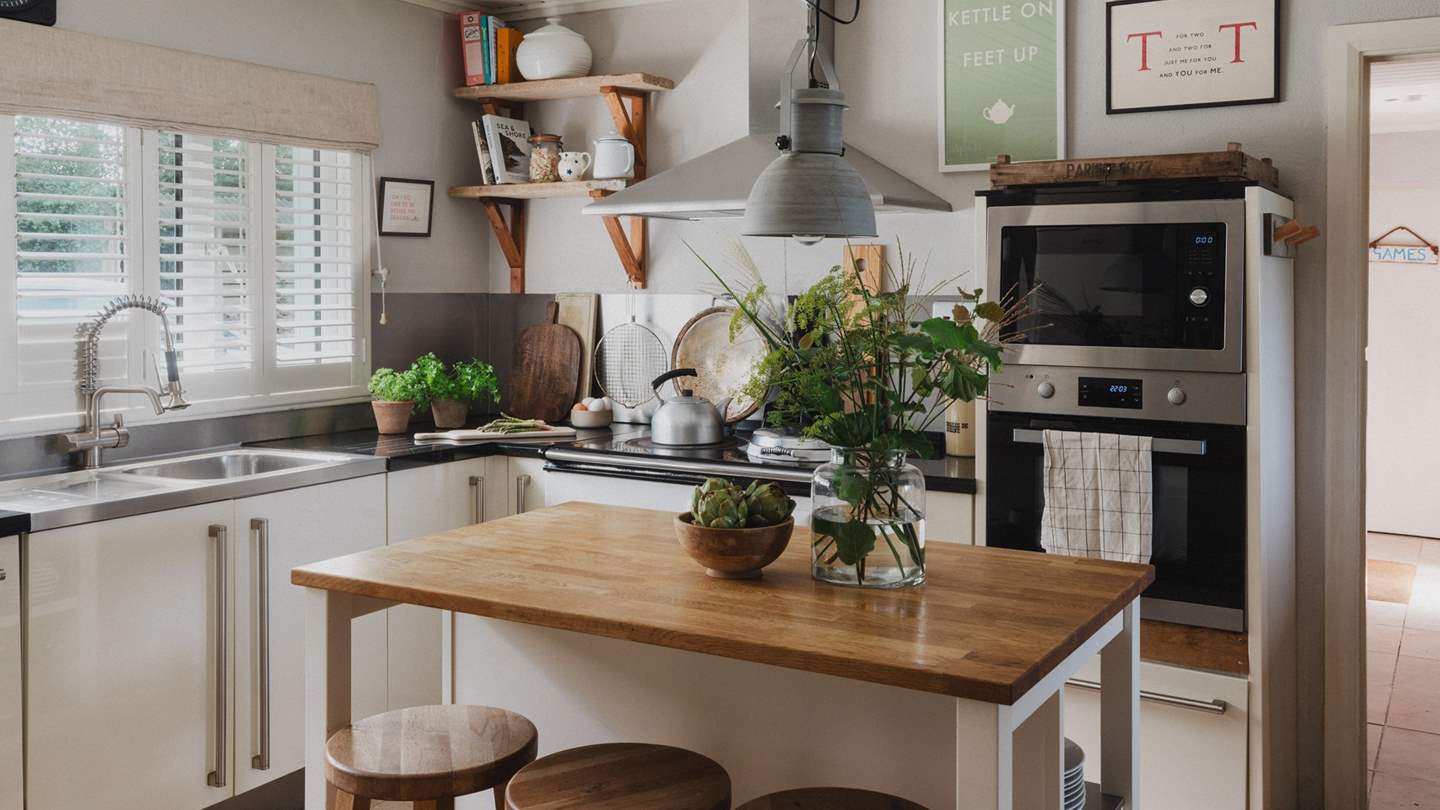 Showcasing open shelves and a stainless steel splashback, it complements its modern styling with eye-catching features and natural inflections