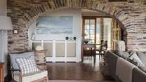 Framed by a stone archway and illuminated by huge windows overlooking Harlyn Bay, the living area is a dream for drawn-out moments savouring ocean aspects