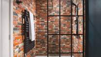 The downstairs shower room has a real New York loft feel to it with exposed brick-effect walls and industrial style fittings 