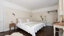 The master bedroom is resplendent in soft creams, crisp whites and lovely dark wood flooring