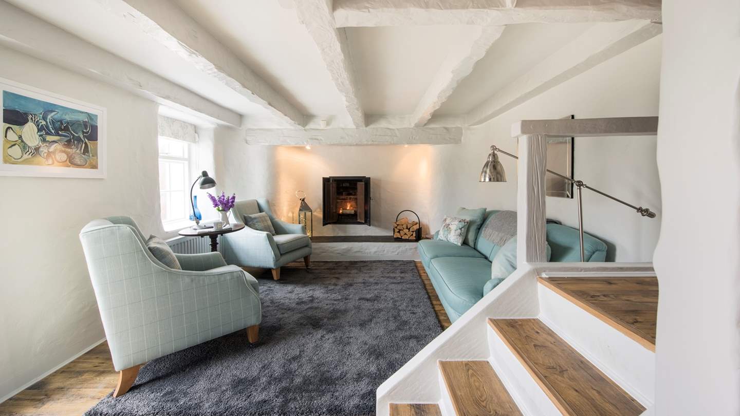 The gorgeously snug living area is simply decorated with rough whitewashed walls, beamed ceiling and a fireplace