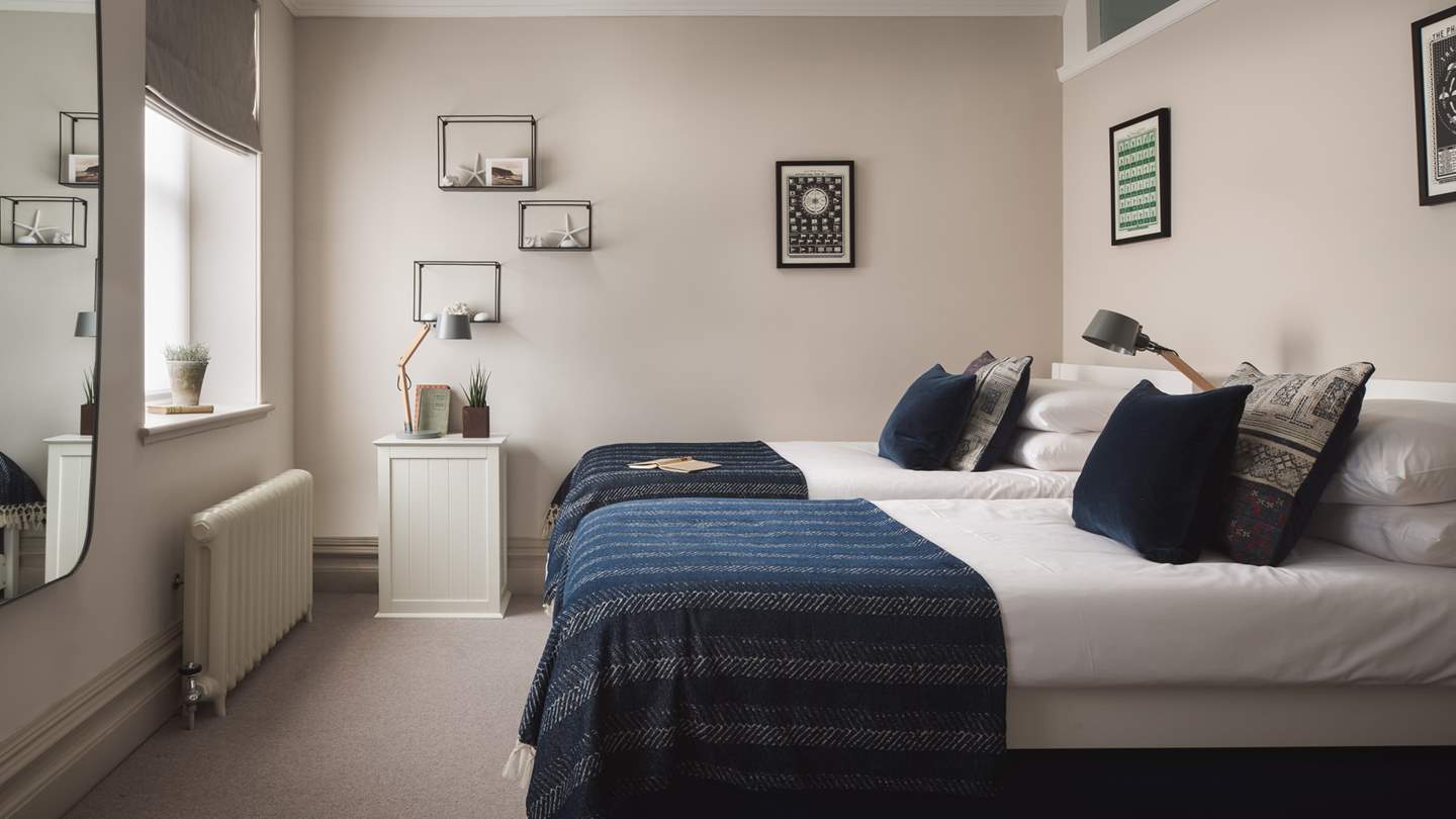 The sleek third bedroom in white and navy tones offers a super-king zip and link, perfect for flexible sleeping arrangements