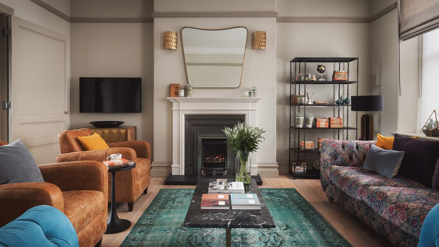 Just next door, you'll find the gorgeous sitting room with jewel-toned furnishings and a beautiful original fireplace