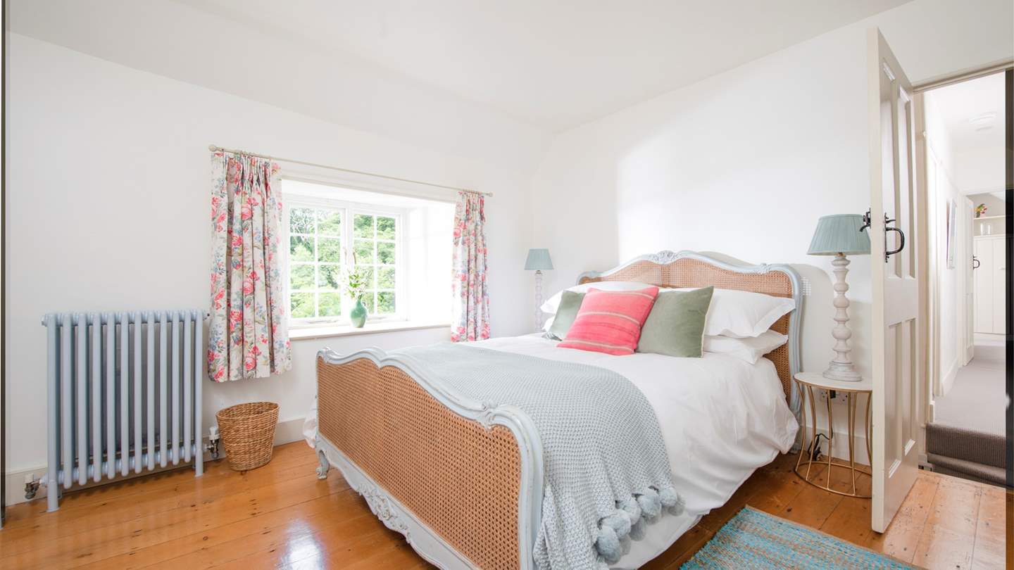 The double bedroom with an antique French country cane bed, original exposed floorboards and lovely garden views.