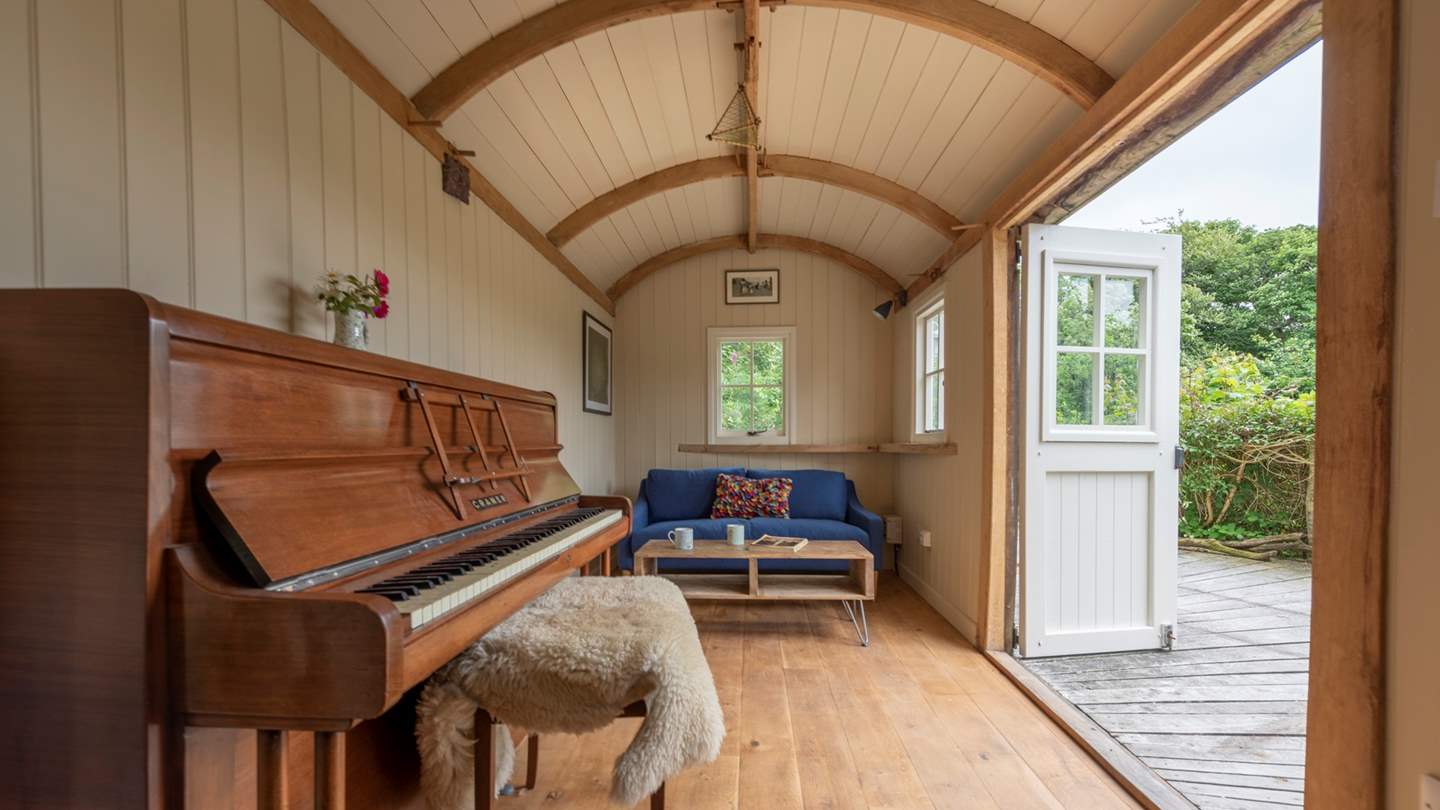 Inside the shepherd's Hut is a sofa, armchair and a piano for tinkling the ivories!