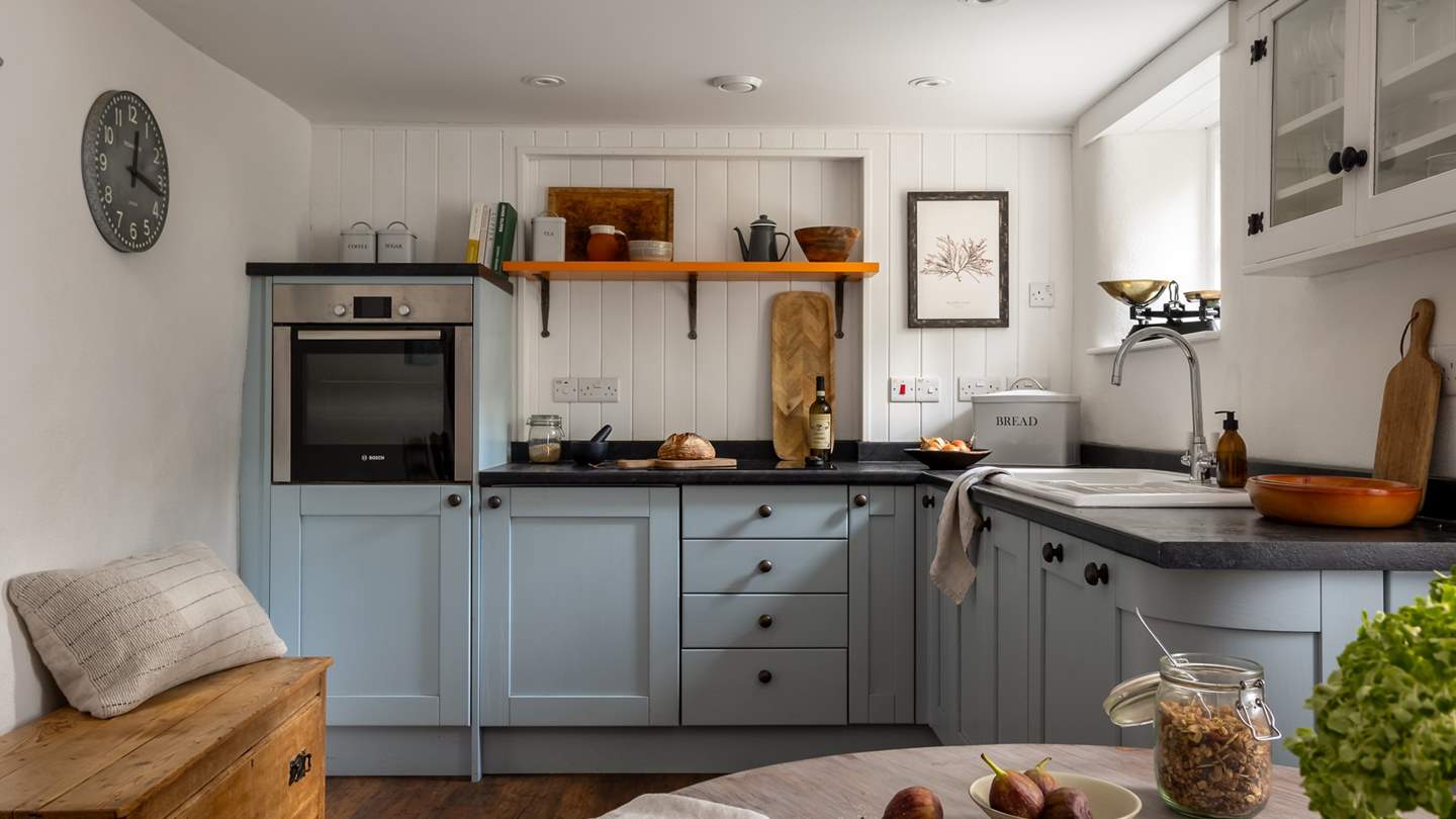 The cute cottage kitchen with eggshell-blue cabinets and white walls comes complete with everything needed to rustle up a feast 