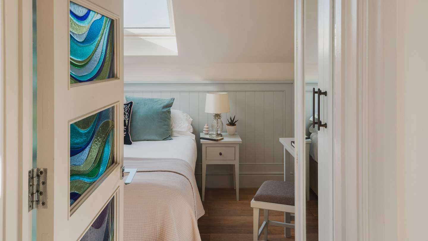 The cosy bedroom hidden behind a stained-glass window, is resplendent in shades of eggshell blue