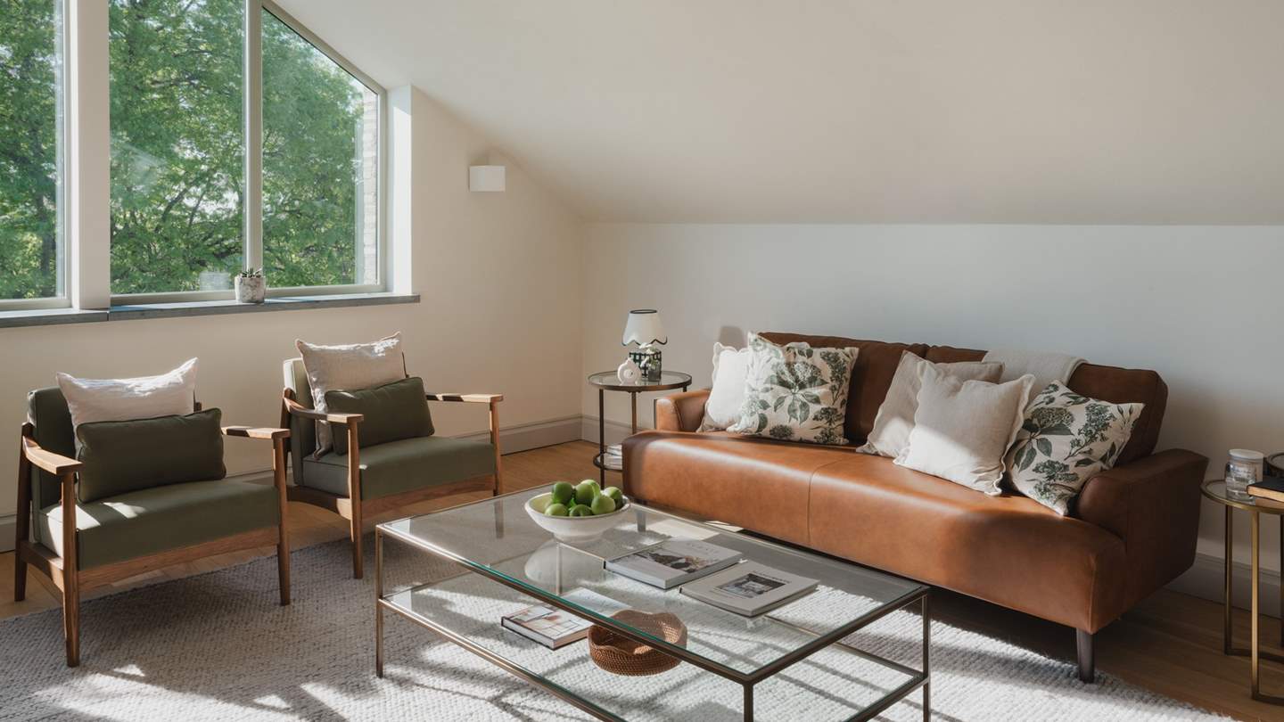 A tan leather sofa and two comfortable armchairs in shades of green await for moments of calm