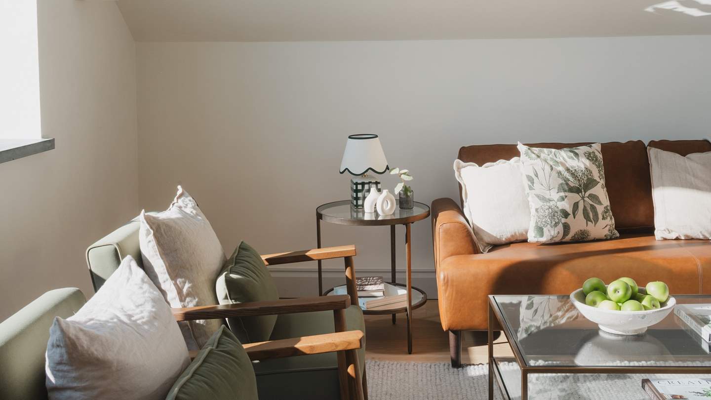 A large glass coffee table and side tables in complementary tones thoughtfully complete this space 