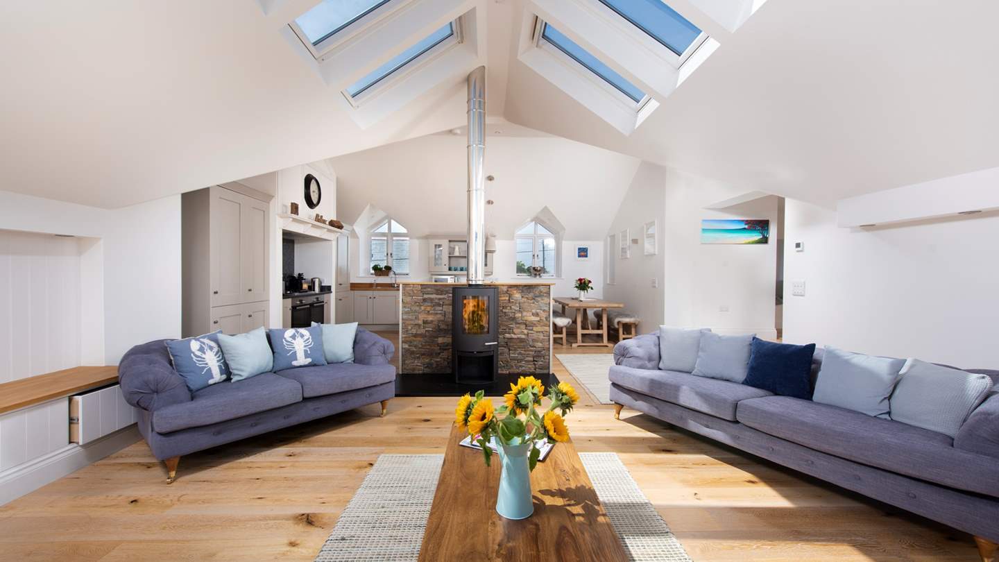 The beautifully light and open-plan living space, with a cosy log-burner nestled in the centre.