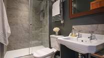 The gorgeously grey shower room has a large walk-in shower for rejuvenating wake-up moments