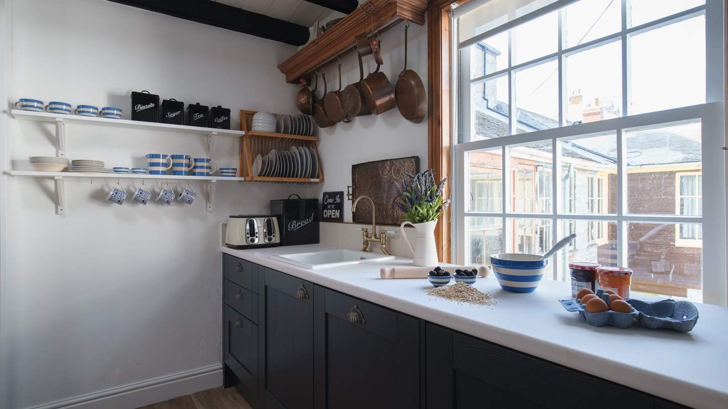 The gorgeous country kitchen is oh-so-pretty with clean white walls, and striking dark blue cupboards