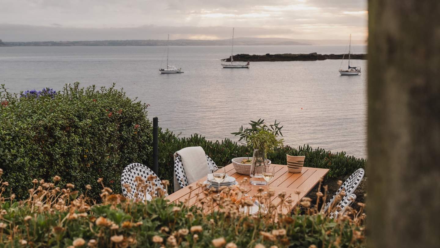 A few steps down the lane through a darling gate, you’ll find a fairytale space surrounded by verdant bushes and sea views