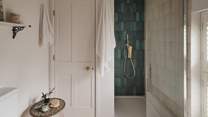 Uncover the walk-in rainfall shower, decorated with beautiful bottle-green and blue tiles