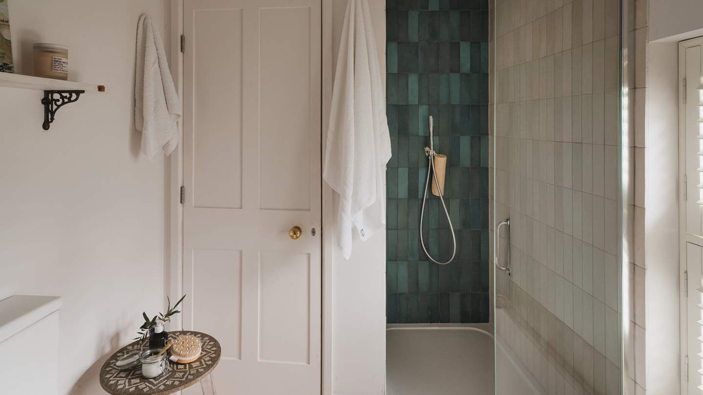 Uncover the walk-in rainfall shower, decorated with beautiful bottle-green and blue tiles
