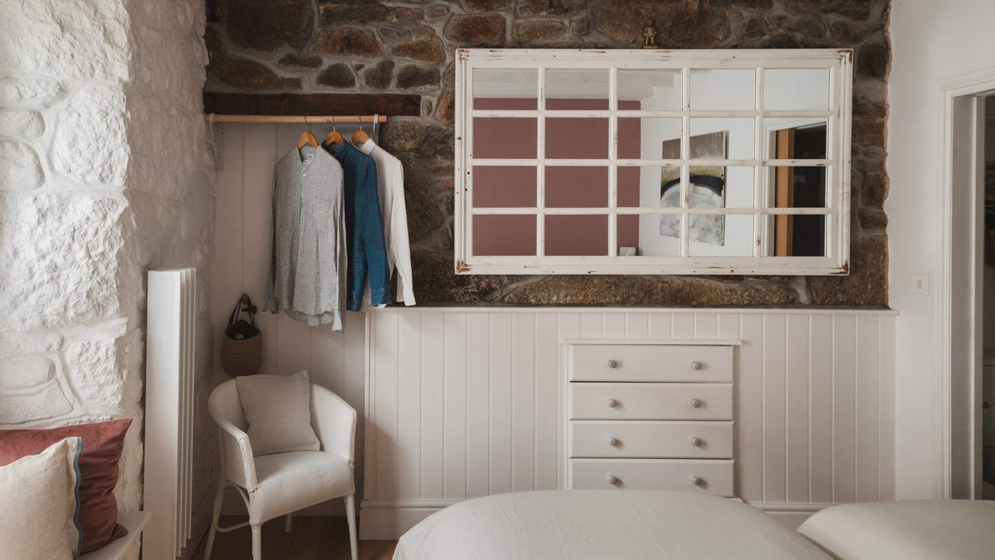 A wardrobe beneath the stairs is equipped for stowing your belongings, while a small desk and chair invite you to sit and plan the day ahead