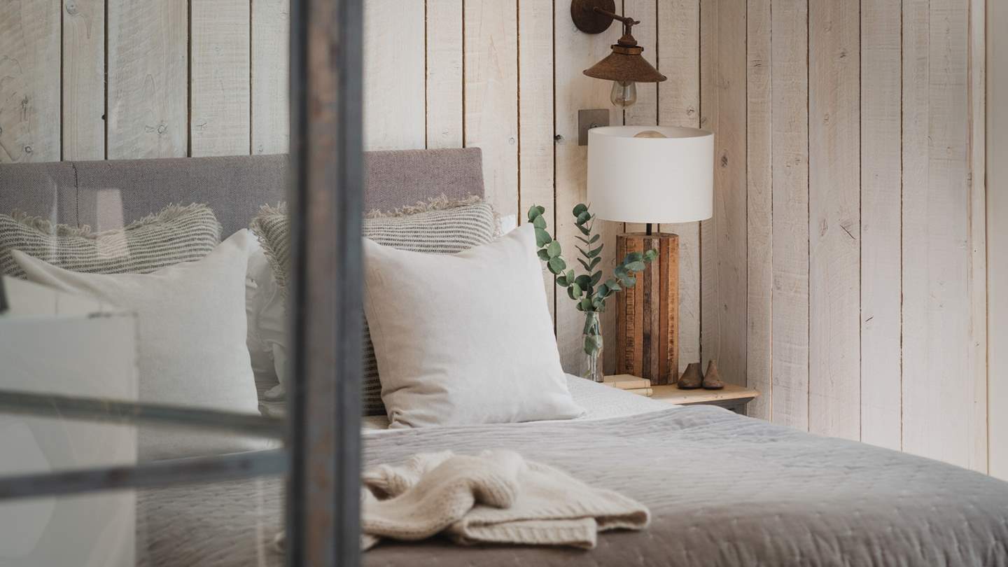 The stunning en suite bedroom lies through industrial-style glass doors