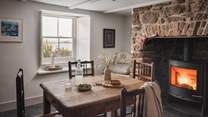 An antique rustic dining table sits before the fireplace for intimate meals fireside

