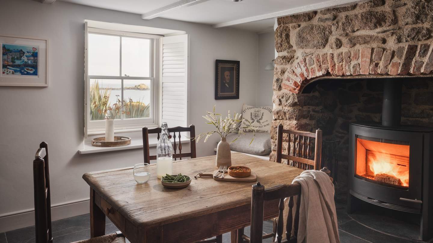 An antique rustic dining table sits before the fireplace for intimate meals fireside

