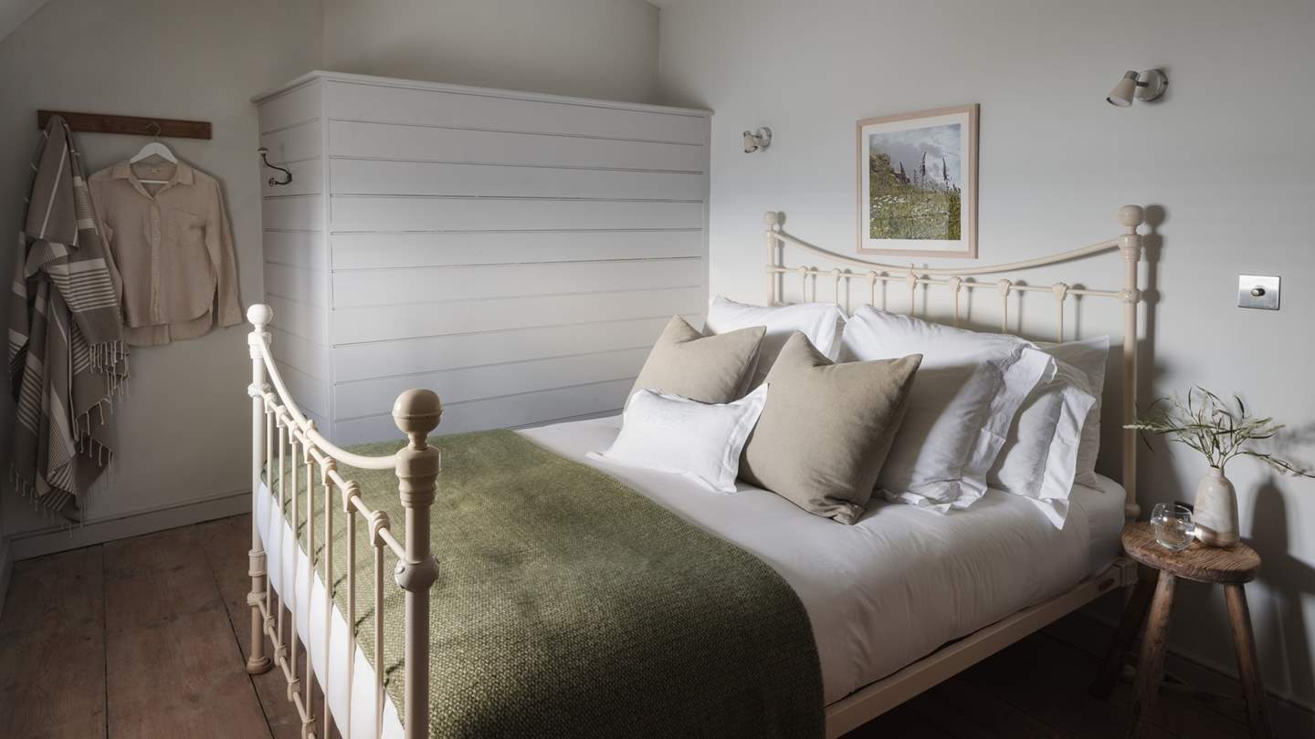 The sweet wrought-iron king size bed dressed in cloud-soft linens, for heavenly slumbers 