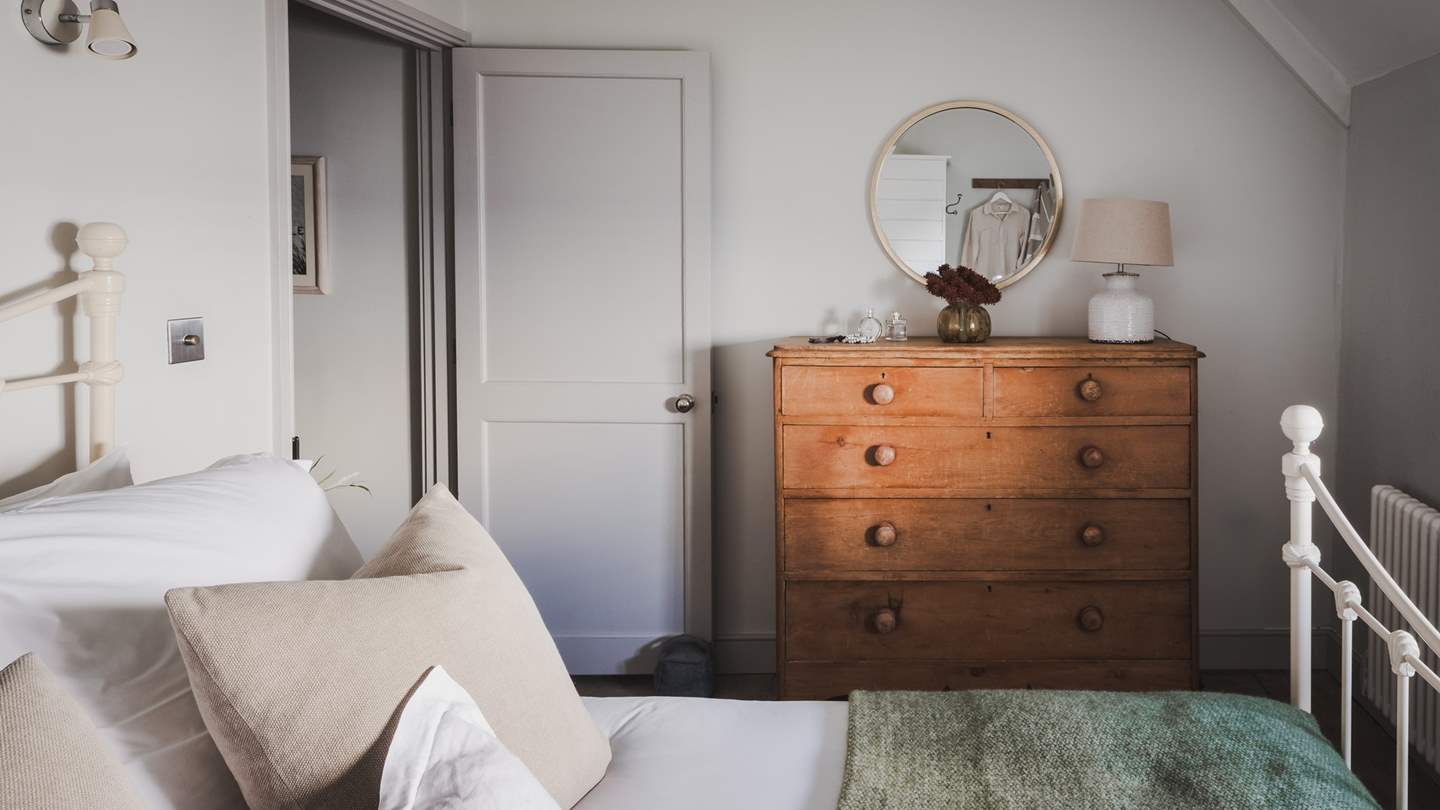 A chest of drawers and hanging space provide space for stowing treasured belongings