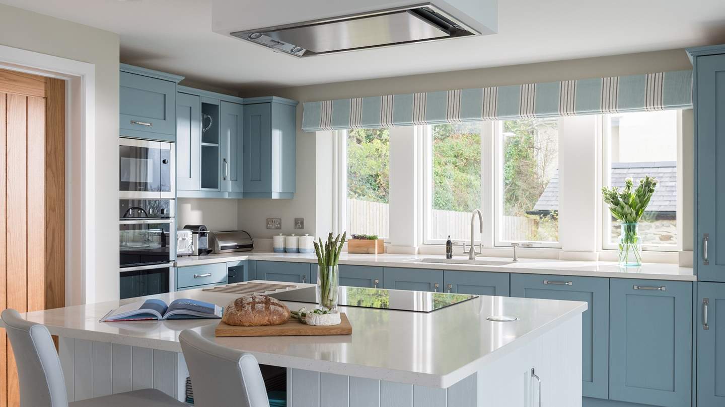 At the other end of the room lies the kitchen, complete with duck egg blue shaker cabinets and white quartz worktop 