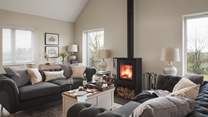 The living room has floor-to-ceiling windows which overlook the garden