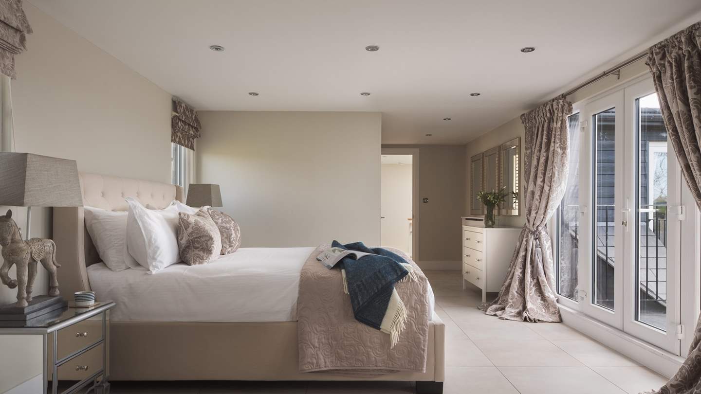 The bedroom to the back of the house is decorated in romantic shades of ivory with a king size bed