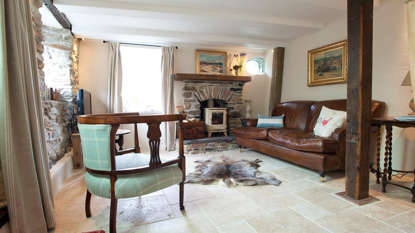 A comfy sofa and a quirky armchair are positioned perfectly to soak up the warmth of the glowing wood burning stove