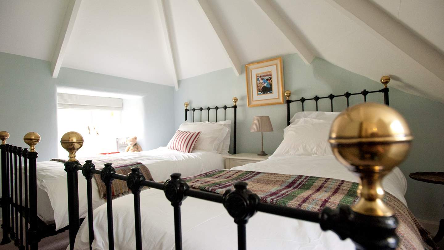 The twin bedroom decorated in a soothing shade of blue, with wrought iron beds dressed in luxurious linens and soft throws