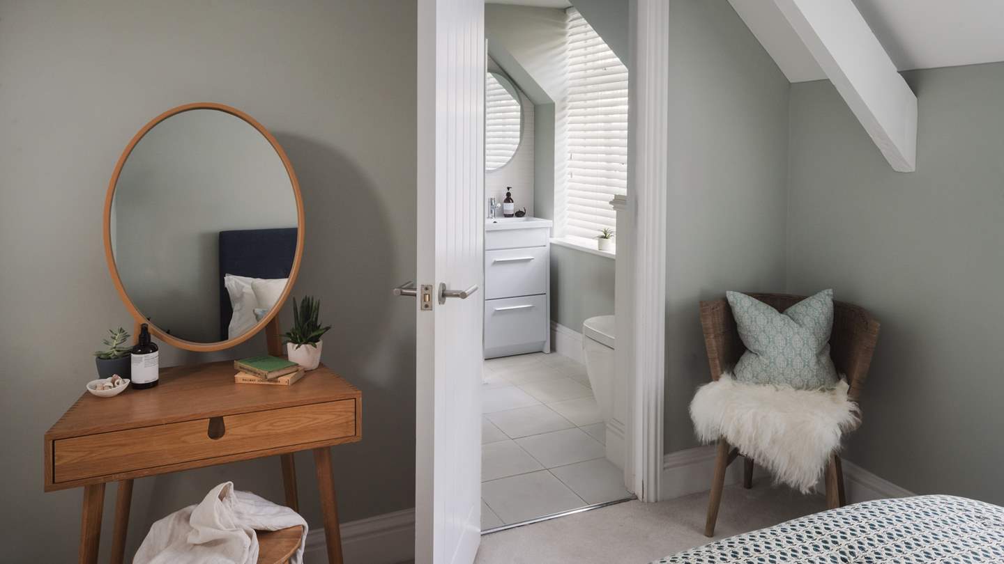 A wicker armchair draped in sheepskin sits next to the window and twin bedside tables hug the bed