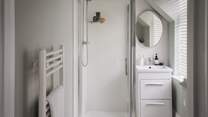 An ensuite bathroom in white completes this bedroom, elegantly finished with a walk-in shower