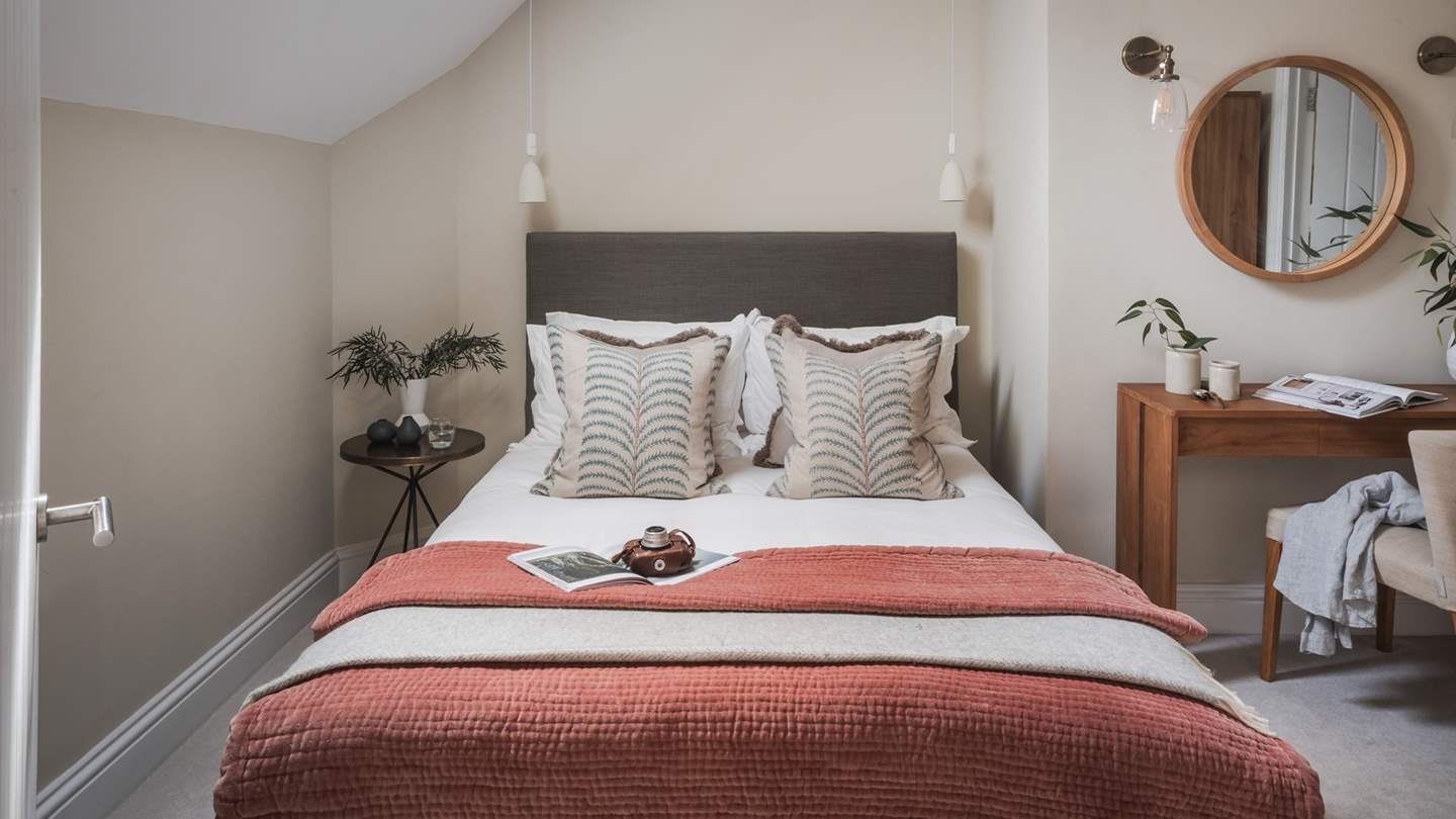 A warm and welcoming haven, the second bedroom features walls of off-white and cream and is decorated in earthy hues