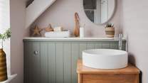 An ensuite bathroom with a walk-in shower adjoins the room, decorated in soft pink and sage tones