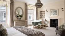 The master bedroom on the second floor, with two gorgeous sash windows, huge super king bed, original fireplace and the pièce de résistance, a wonderful bath
