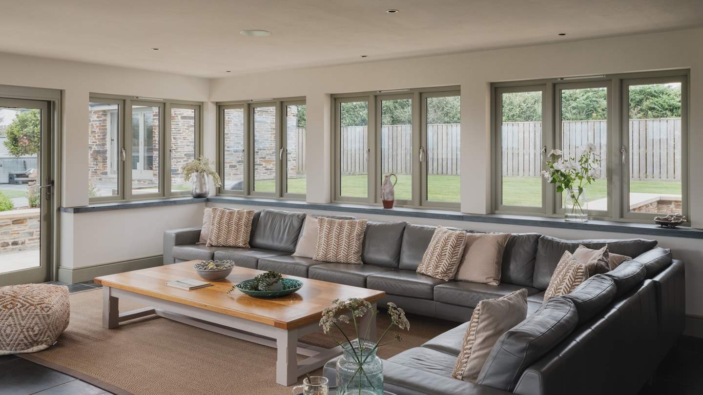 The sitting room has a huge, super-soft sofa which seats ten, an armchair, coffee table,  Smart TV, SONOS sound system and glass doors that open out to the perfectly landscaped garden