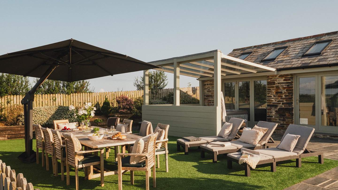 For alfresco meals and moments in the sunshine, it features a table and chairs, as well as three sun lounger chairs adorned with cushions