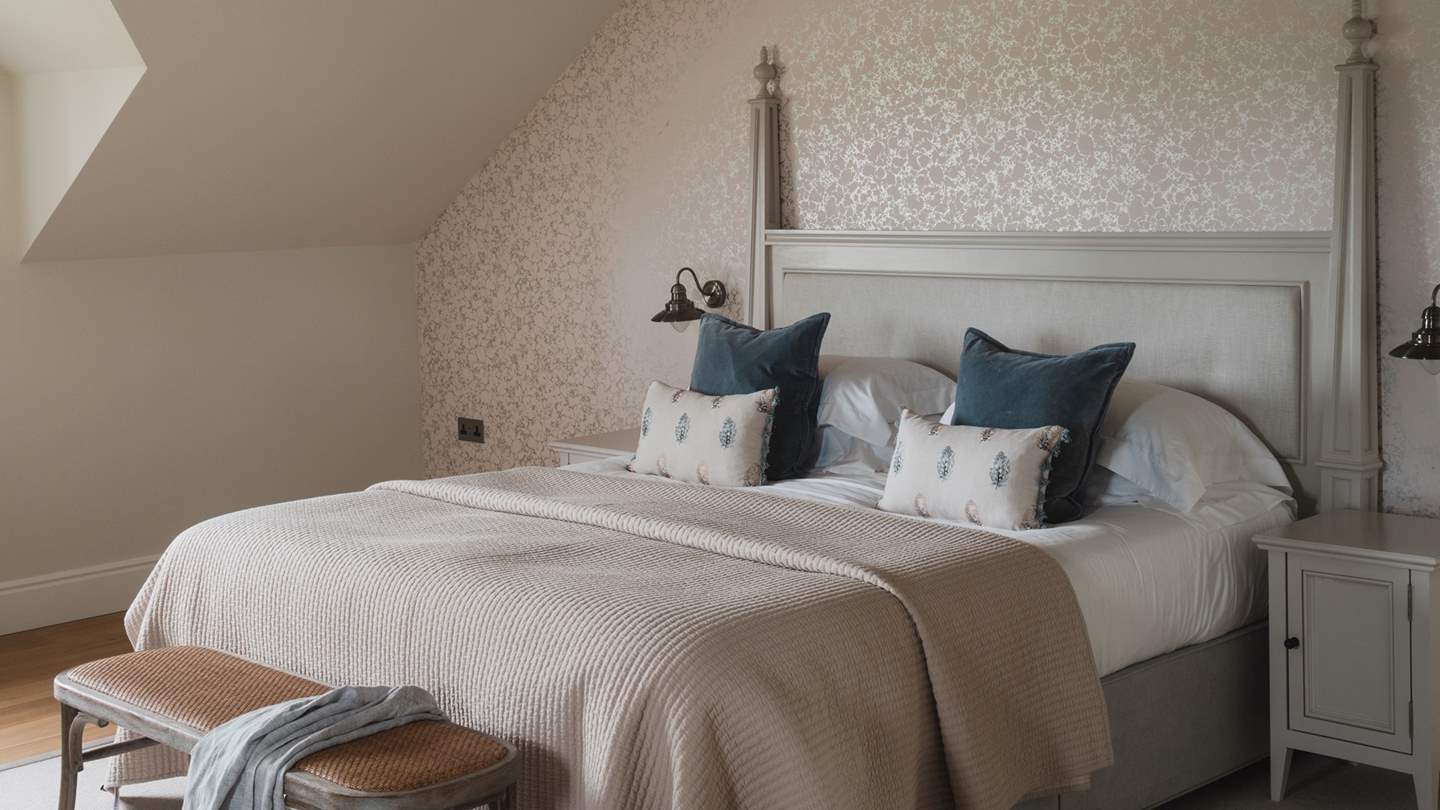 Wooden side tables hug the bed, with wall lights fitted above for drawn-out lie-ins