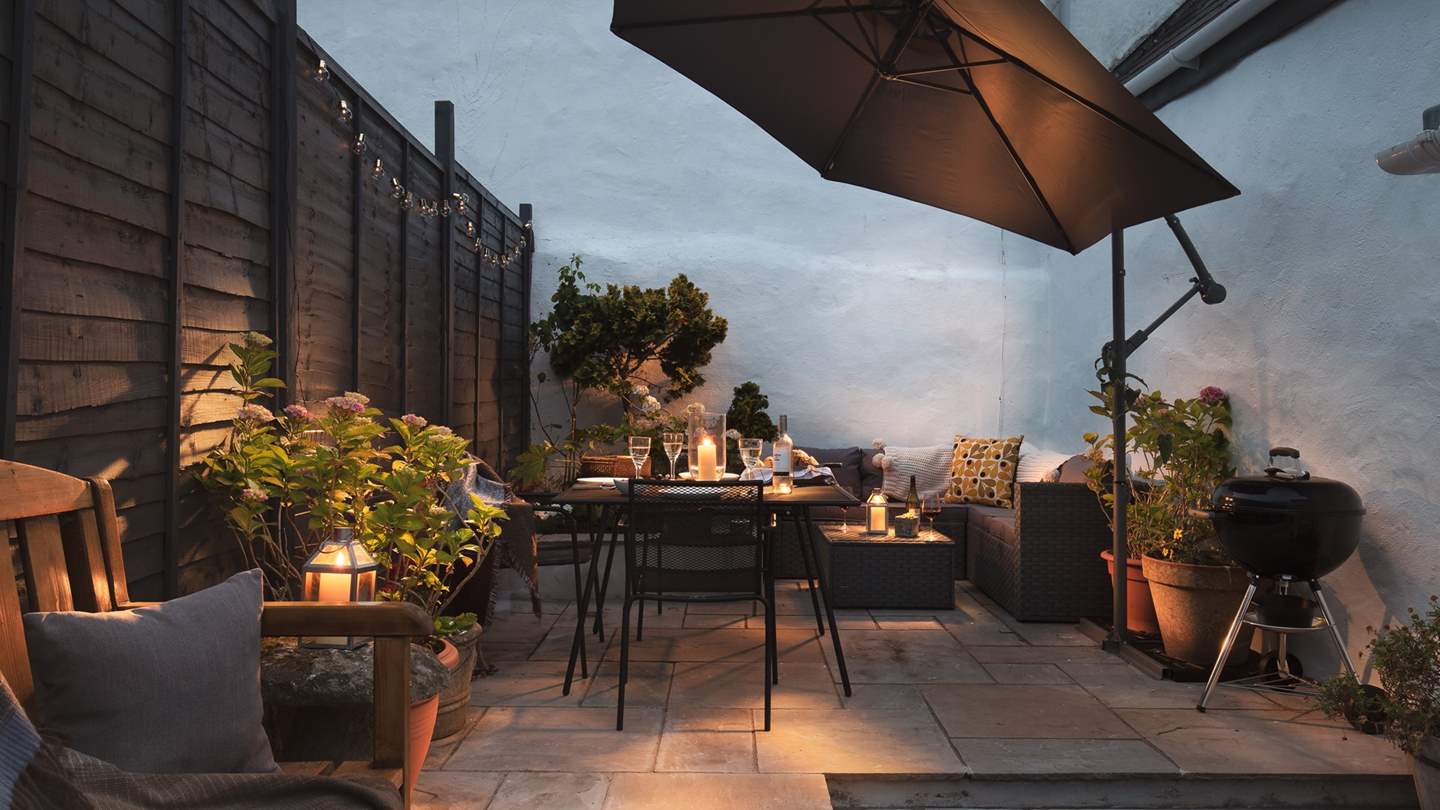 The pretty courtyard garden with a table and chairs for outside dining plus a coal barbeque. Please note the cantilever umbrella has been replaced with a wooden pergola