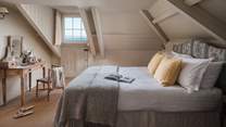 Set amongst the eaves on the second floor lies another sea-view bedroom space