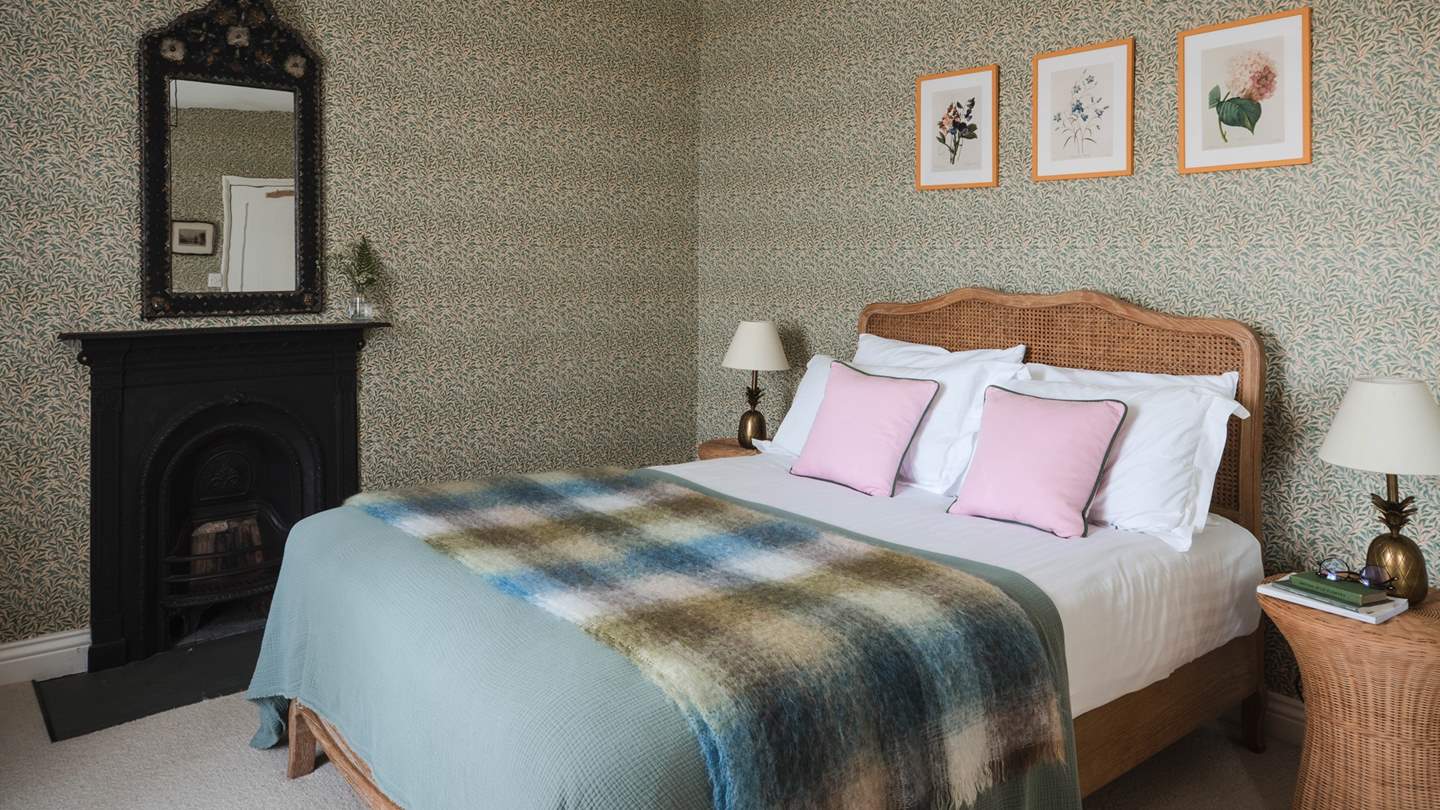Complete with an original fireplace and adorable botanical prints, this bedroom is effortlessly striking
